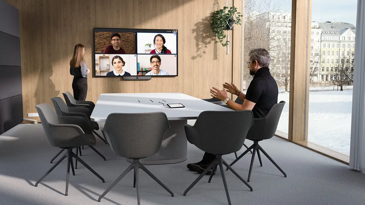 Collaborateurs participant à une réunion hybride dans une salle équipée